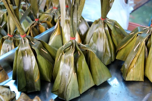 Thai Dessert , Steamed Coconut Custard with Sweet Coconut Filling in banana leaf package selling in Thailand street market photo