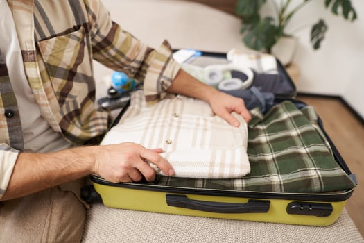 Male hands, tourist packs his clothes inside suitcase, puts items inside luggage to go on holiday, plans vacation, travels abroad photo