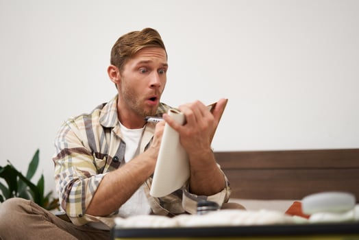 Portrait of tourist checking his notes, making list of items for holiday, writing down ideas, packing suitcase, sitting on bed, getting ready for vacation photo