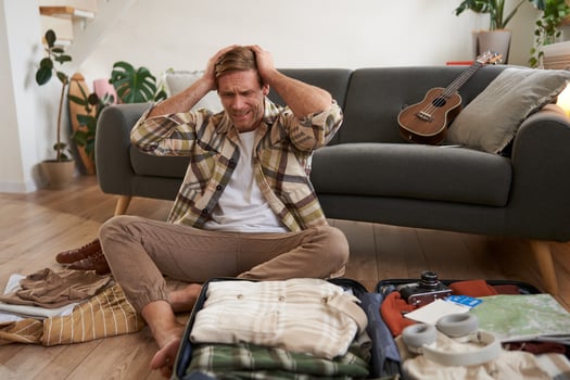 Portrait of guy in panic, packs suitcase, looks stressed and worried, clueless what to bring on holiday photo