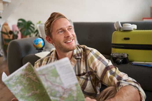 Portrait of handsome smiling guy, tourist going on holiday, holding map, plans where to go on vacation photo