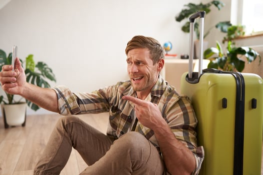 Portrait of smiling handsome man with suitcase, taking selfie with luggage, posting on social media about going on holiday photo