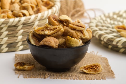 Dry figs served in bowl isolated on napkin side view of dry fruits on grey background photo
