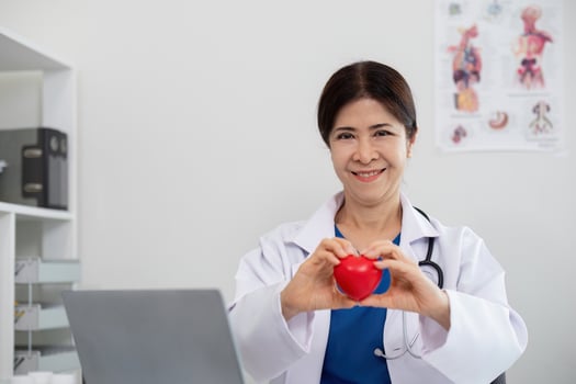 Happy young doctor senior woman holding red heart shape object, looking at camera with smile. Positive practitioner, cardiologist photo
