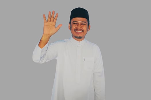 moslem man walking and waving hand to greet someone with happy expression photo