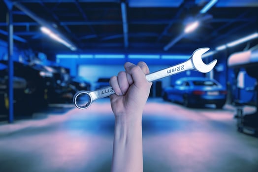 Wrench held in hand inside a car service garage. Illustrating the car service concept with automotive repair and maintenance photo