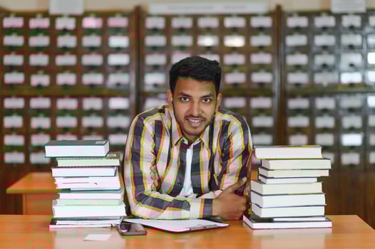 Happy smart indian or arabian guy, mixed race male, university student, in the library photo