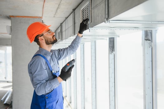 Industrial Theme. Warehouse Heating and Cooling System Installation by Professional Caucasian Technician. Commercial Building Ventilation Rectangle Canals. Air Distribution. photo