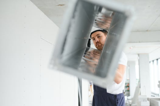 Industrial Theme. Warehouse Heating and Cooling System Installation by Professional Caucasian Technician. Commercial Building Ventilation Rectangle Canals. Air Distribution. photo
