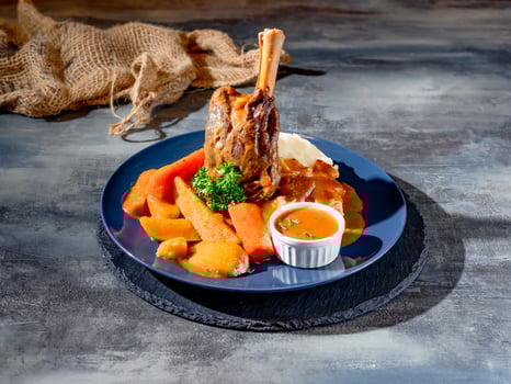 Rosemary roasted Lamb Shank with sauce in a dish top view on dark background photo