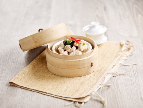 Steamed Spare Ribs with Diced Yam served in a wooden bowl with chopsticks isolated on mat side view on grey marble background photo