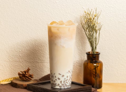 Iced Winter Melon Fresh Milk Taro tea served in disposable glass isolated on wooden board side view of taiwanese ice drink photo