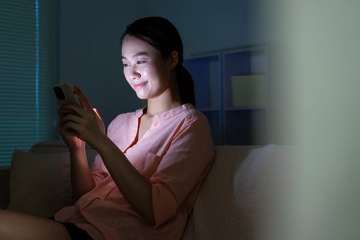 Young Asian woman using phone in the dark at night photo