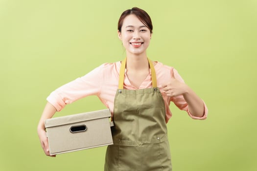 Photo of young Asian female housekeeper on green background