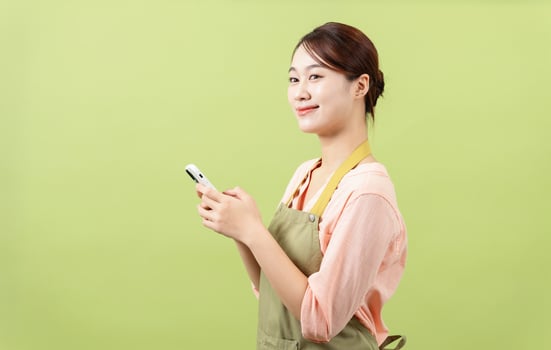 Photo of young Asian female housekeeper on green background