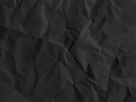 Black crumpled paper texture in low light background photo