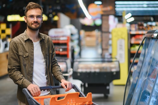 Handsome smiling man shopping in supermarket pushing trolley photo