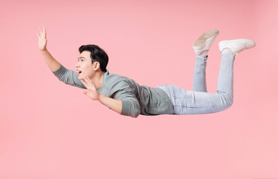 Photo of young Asian man flying on background