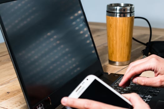 Woman using mobile phone in the office with a laptop and a coffee photo