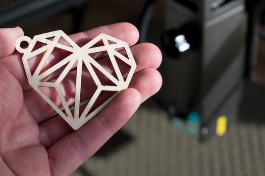 Laser engraving and cutting, hand holding an example of a cut out wooden heart photo