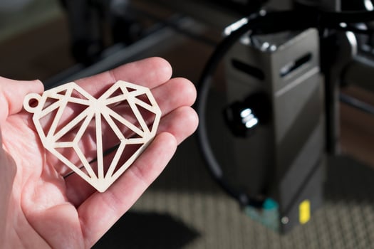 Laser engraving and cutting, hand holding an example of a cut out wooden heart photo