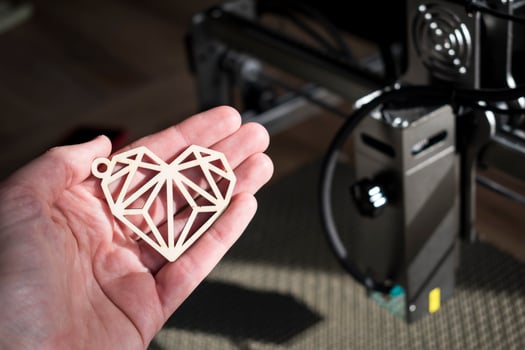 Laser engraving and cutting, hand holding an example of a cut out wooden heart photo