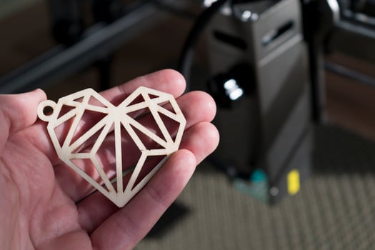 Laser engraving and cutting, hand holding an example of a cut out wooden heart photo