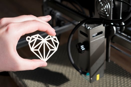 Laser engraving and cutting, hand holding an example of a cut out wooden heart photo