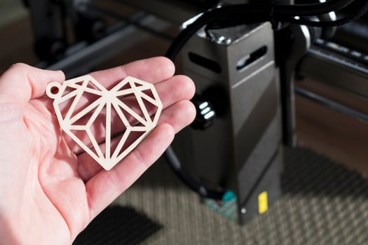 Laser engraving and cutting, hand holding an example of a cut out wooden heart photo