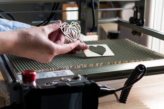 Laser engraving and cutting, woman holding an example of a cut out wooden heart photo