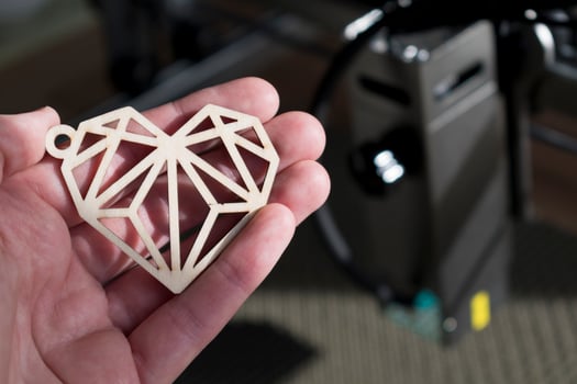 Laser engraving and cutting, hand holding an example of a cut out wooden heart photo