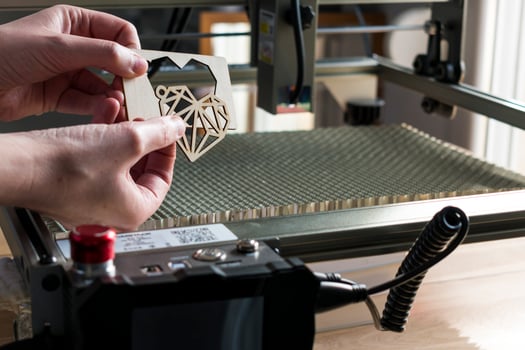 Laser engraving and cutting, woman holding an example of a cut out wooden heart photo