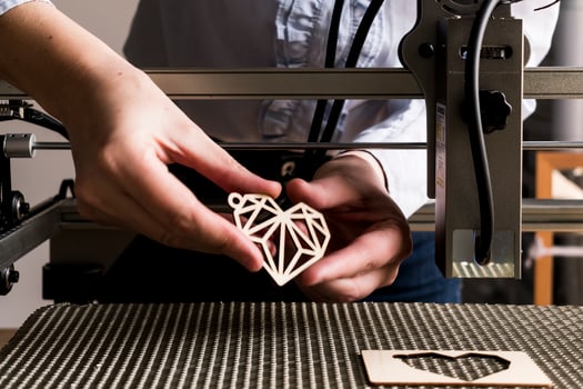 Laser engraving and cutting, woman holding an example of a cut out wooden heart photo