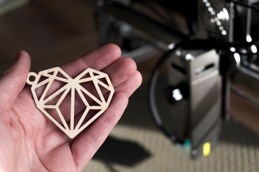 Laser engraving and cutting, hand holding an example of a cut out wooden heart photo