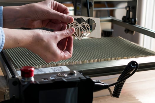 Laser engraving and cutting, woman holding an example of a cut out wooden heart photo
