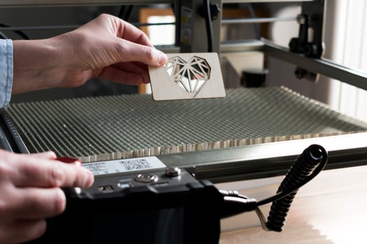 Laser engraving and cutting, woman holding an example of a cut out wooden heart photo