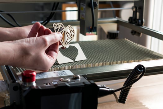 Laser engraving and cutting, woman holding an example of a cut out wooden heart photo