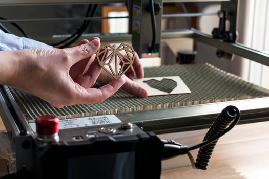 Laser engraving and cutting, woman holding an example of a cut out wooden heart photo