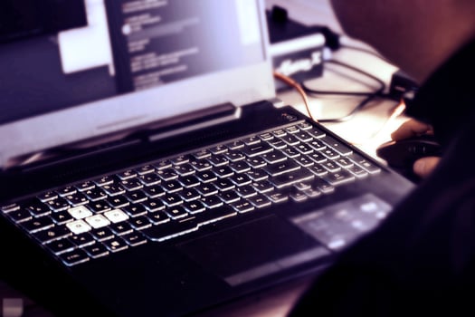 Close up of man's hand using wireless mouse and laptop computer with blue backlit keyboard photo