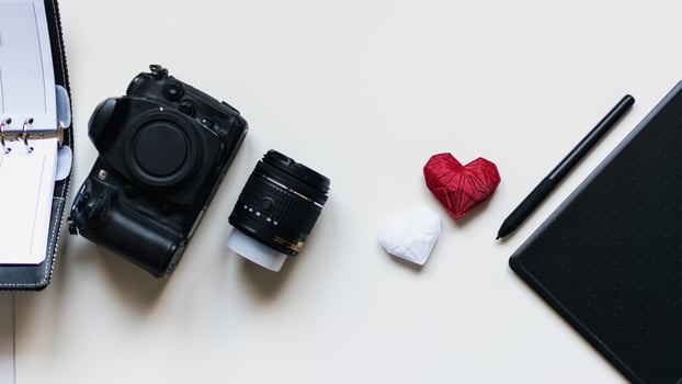Graphic designer workstation with dslr, lens, agenda, stylus and heart printed in 3d photo