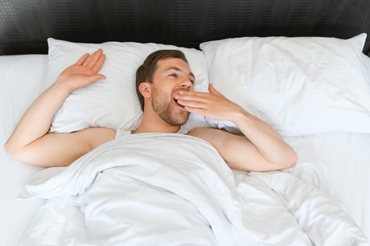 Young man sleeping waking up and stretching in his bed photo
