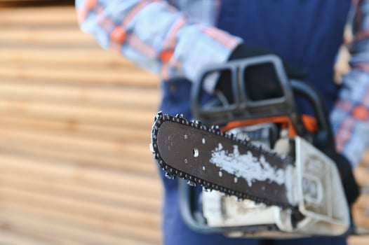 Carpenter with a saw in his hands stands on a background of cut wooden boards. photo
