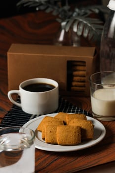 Crunchy cookies biscuits served in plate with cookie box, black coffee and glass of milk isolated on table side view of american cafe baked food photo
