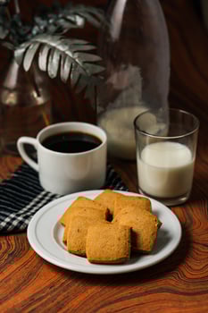 Crunchy cookies biscuits served in plate with black coffee and glass of milk isolated on table side view of american cafe baked food photo