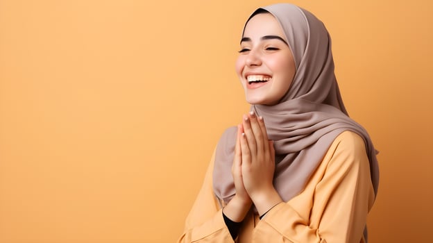 European woman wearing scarf is praying and smiling on orange background photo