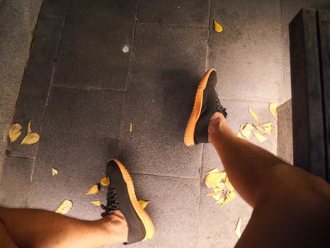 legs and feet of a man wearing sneakers On a cement floor strewn with flower petals At night the lights shine on photo