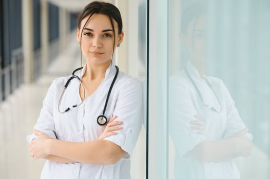 Portrait of young female doctor standing in hospital corridor. Caucasian woman working in nursing home. photo