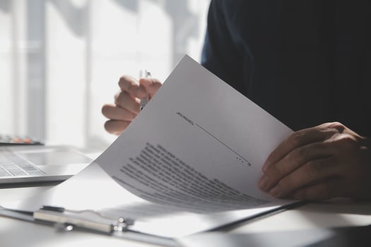 Asian businessman reviewing document reports at office workplace with computer laptop. legal expert, professional lawyer reading and checking financial documents or insurance contract photo