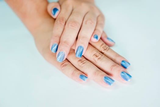 Hands of an Asian woman decorating nails with pearl blue paint. photo