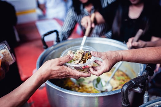 Feeding Concepts . Hand offered to donate food from a rich man Share. The concept of social sharing . Poor people receiving food from donations photo